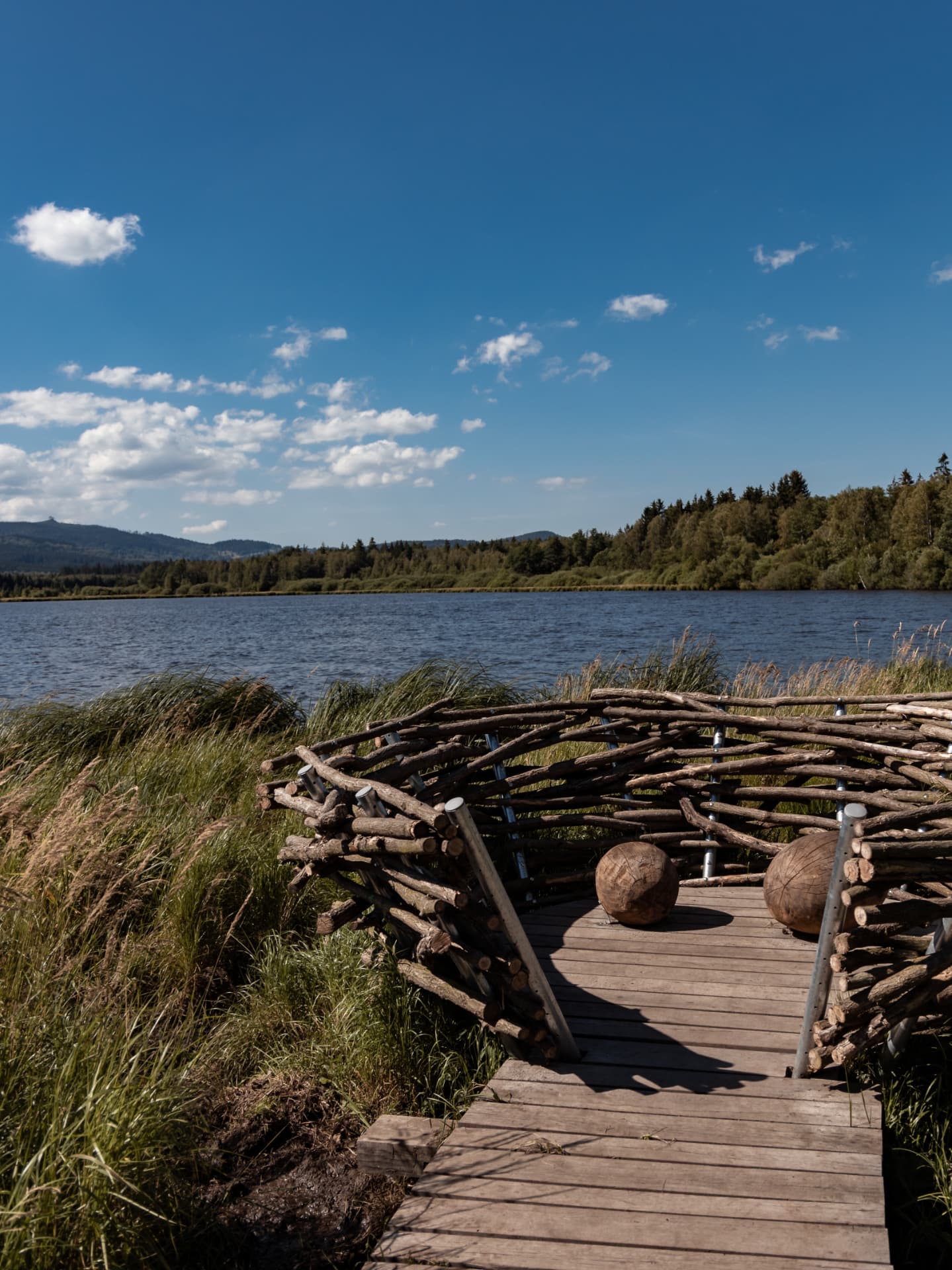 A wooden boardwalk and a woven bird hide beside the Olšina pond