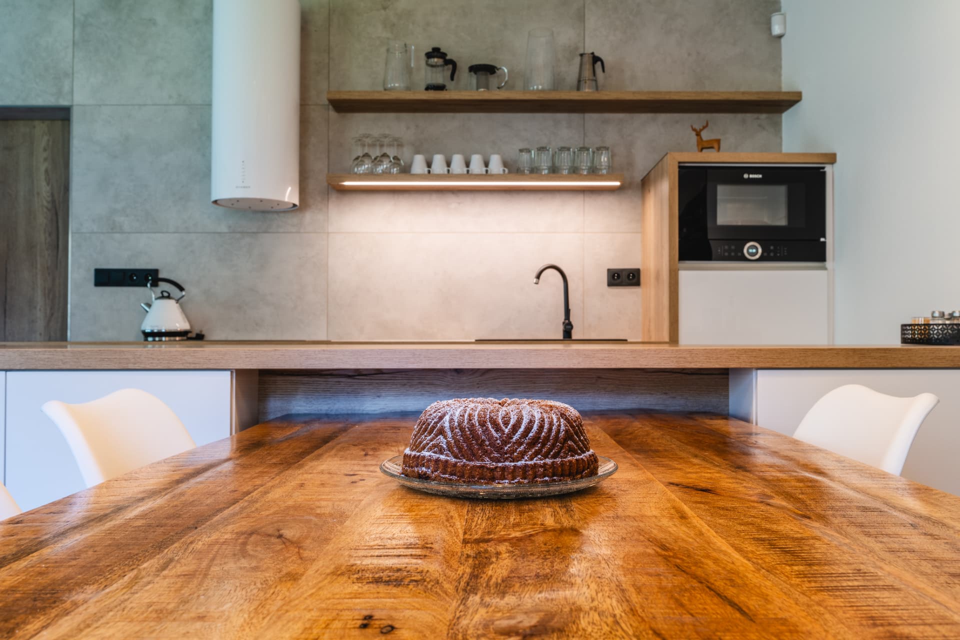 Dining table with a cake and a fully equipped kitchen in a HYGGE apartment