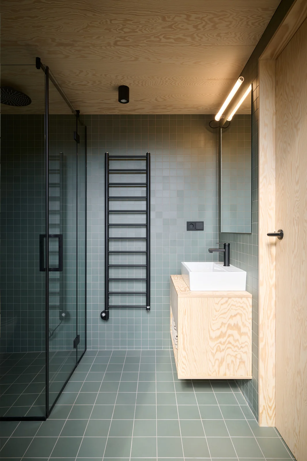 Bathroom with green tiles and a plywood vanity