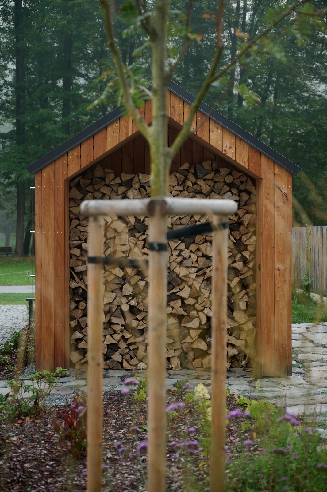 The wooden log store filled with firewood in the garden