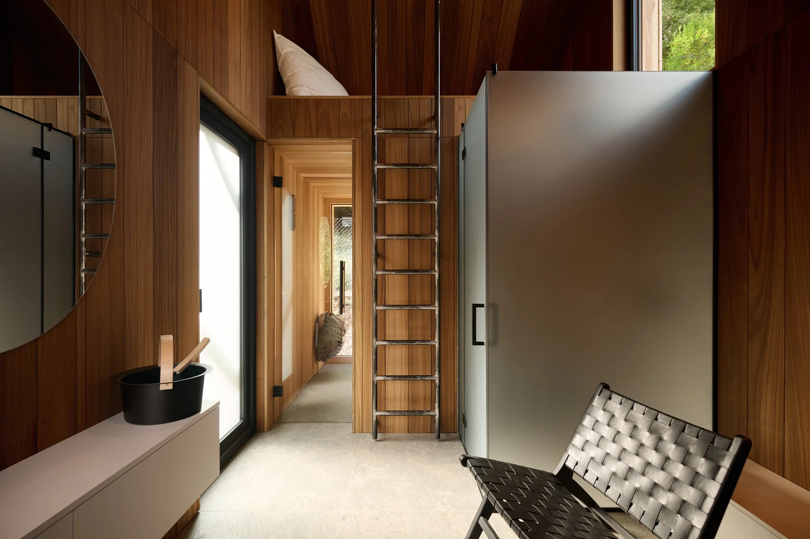 The sauna hall with a bucket, mirror and ladder to the sleeping loft