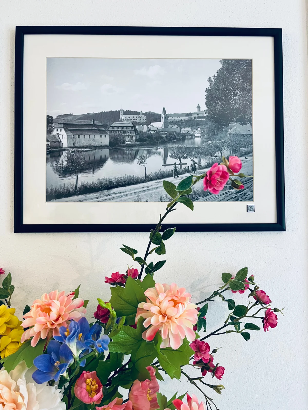 Bouquet beneath a framed historic photograph of Rožmberk