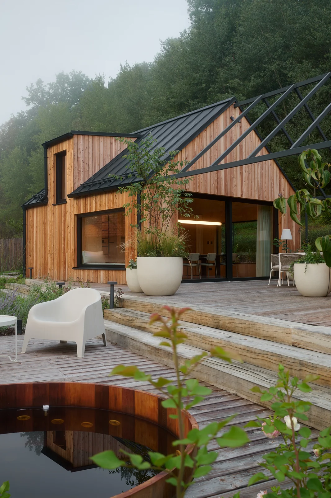 The deck with the cedar hot tub and the timber house beyond